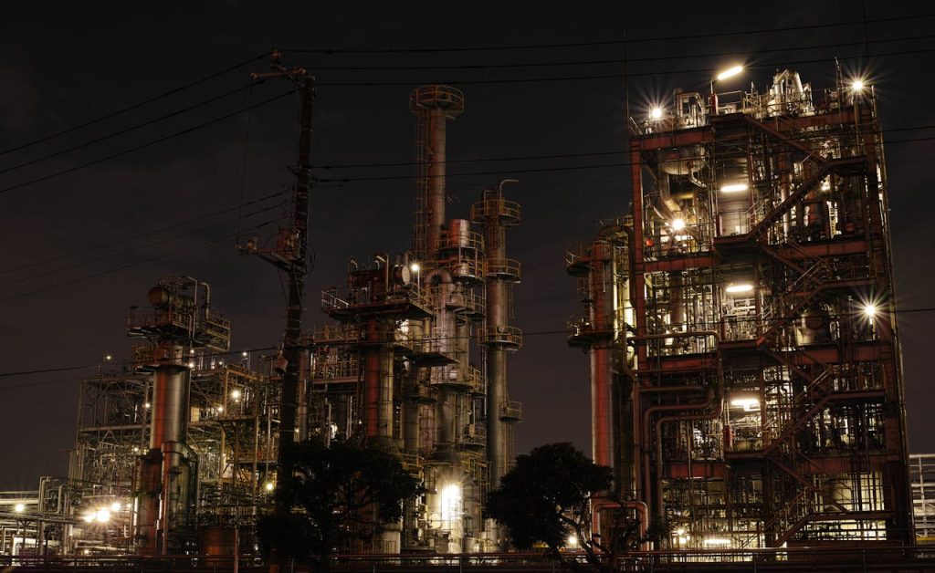 Night view of a brightly lit industrial facility showcasing intricate steel structures and machinery.